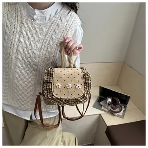 Détail d'un mini sac à dos avec broderie florale blanche et pois marrons avec des volants