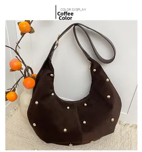 Detalle de bolso hobo de ante marrón con tachuelas doradas sobre fondo interior