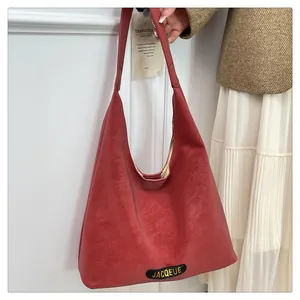 Close-up of a brick red leather hobo bag with a gold embossed JACQUEUE brand tag