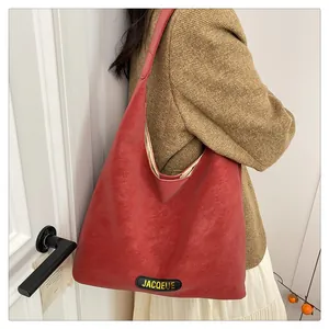 Detail view of large red tote bag in matte PU leather worn by a model in casual blazer