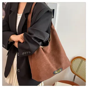 Close-up of brown leather tote bag with wide strap and JACQEUE logo patch detail