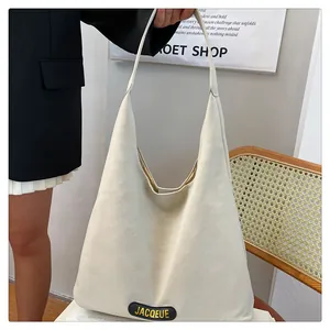 Detail view of cream oversized tote bag with branded oval patch and wide shoulder strap