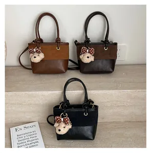 Detailansicht der Patchwork-Eimertaschen aus Wildleder mit Plüschbären-Anhängern in Braun