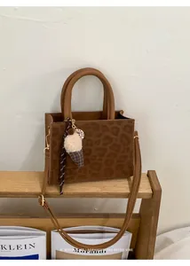 Details der Umhängetasche mit Leopardenmuster und Eiscreme-Anhänger aus Holz