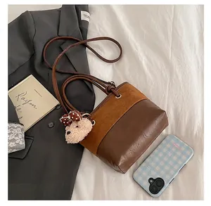 Detail of suede bucket bag featuring contrast textures and a cute plush bear charm