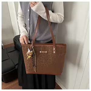 Detalle del bolso shopper de leopardo con placa dorada y colgante de osito de peluche