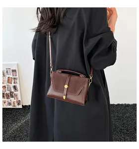 Detail of dark brown leather handbag showing mixed matte and smooth textures with gold buckle