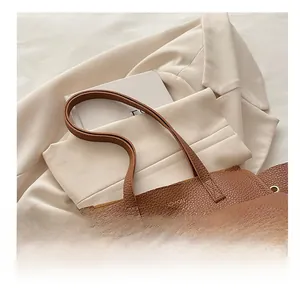 Détail d'un sac cabas en cuir marron à texture litchi avec logo doré et poche frontale