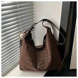 Detail der Hobo-Schultertasche mit Leopardenmuster und Baseball-Anhänger-Dekoration