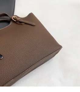 Close-up of brown litchi grain leather bag with white contrast stitching and metal buckle