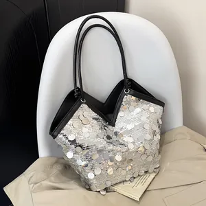 Sac fourre-tout à paillettes argentées et lanières noires sur un trench beige