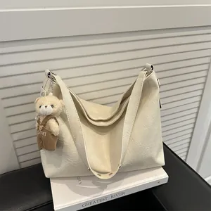 Grande borsa tote beige vintage con trama morbida e ciondolo a forma di orso su un libro