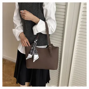 Detail of dark brown pebble leather tote bag with printed silk scarf on the handle