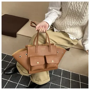 Gros plan d'un sac cabas marron avec œillets métalliques et texte fashion sur escalier