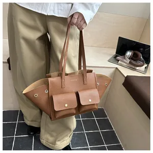 Détail du sac cabas en cuir marron avec design ailé et poches avant à rabat