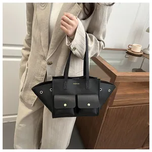 Détail d'un sac cabas en cuir grainé noir avec design en ailes et boucles métalliques