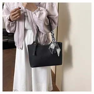 Detail view of black pebble leather tote with contrast stitching and silk scarf wrap