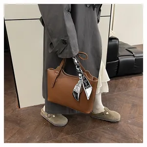 Detail of brown litchi leather tote bag with silk scarf wrapped on the slim handles