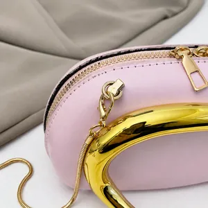 Détail du sac rose montrant la poignée en métal doré, la chaîne et les crochets dorés