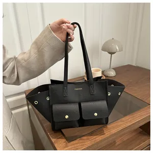 Gros plan du sac cabas noir en cuir grainé avec boutons dorés et poches frontales