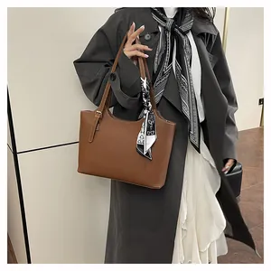 Close-up of brown leather tote bag with elegant silk scarf and gold hardware details