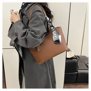 Detail of brown litchi pattern leather tote bag featuring a black and white silk scarf
