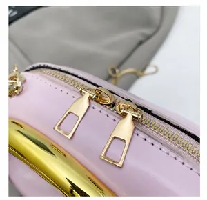 Vue détaillée des fermetures éclair dorées et de la texture cuir rose du sac de ville