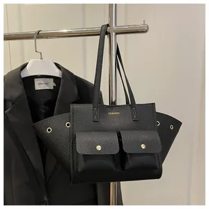 Vue détaillée d'un sac cabas en cuir grainé noir avec boucles dorées et poches avant à rabat