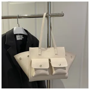 Gros plan du sac fourre-tout en cuir crème avec texture litchi et deux poches avant boutonnées