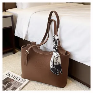 Detailed macro view of brown lychee grain leather tote bag featuring elegant silk scarf detail