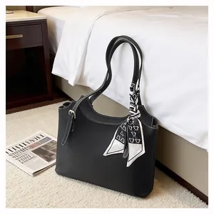 Close-up of black litchi grain leather tote with contrast stitching and silk scarf