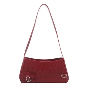 Deep red shoulder bag with decorative leather cross straps and metal oval buckle