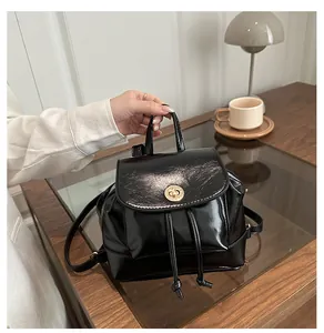 Détail du mini sac à dos noir brillant avec fermoir doré et poignée en cuir élégant