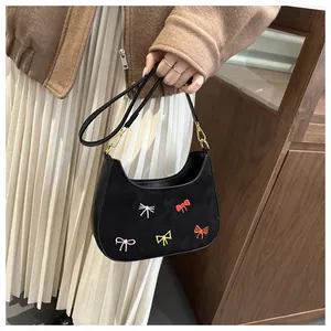 Détail d'un mini sac en daim noir avec broderies de nœuds colorés et fermoir doré