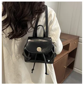 Vue arrière d'un mini sac à dos noir en similicuir avec fermoir doré porté par un mannequin