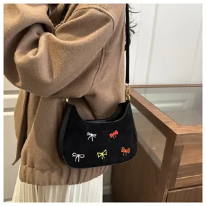Détail du sac à main en daim noir avec broderie papillon colorée et boucle en métal