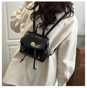 Détail d'un petit sac à dos en cuir noir avec fermoir doré et cordon de serrage