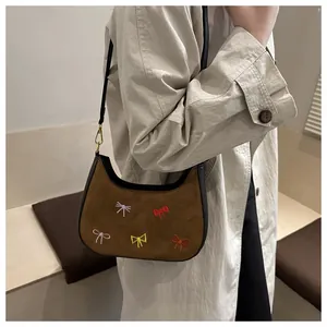 Détail d'un sac hobo en daim marron avec broderies de nœuds colorés et bandoulière