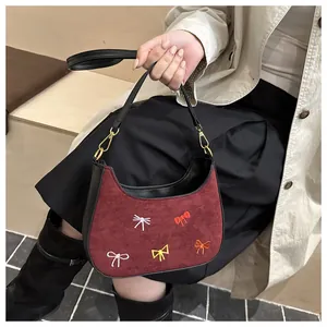 Gros plan détaillé du sac à main en daim bordeaux avec broderies de nœuds colorés