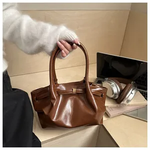 Détail d'un sac cabas marron en cuir PU brillant avec plis élégants et boucle en métal doré