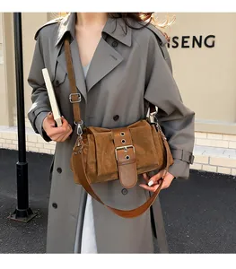 Detail of caramel brown suede baguette bag with pleated texture and metal buckle