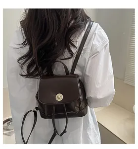 Détail d'un petit sac à dos en cuir marron foncé avec fermoir doré et cordon