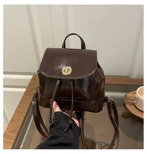 Détail d'un mini sac à dos marron brillant avec fermoir doré rotatif et cordon de serrage