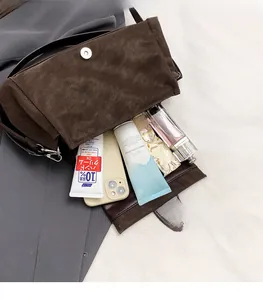 Detail view of coffee suede baguette bag showing spacious interior and magnetic closure