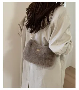 Détail de la texture en fausse fourrure grise et de la plaque dorée sur le sac à bandoulière