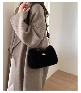 Gros plan d'un sac à bandoulière en peluche noire avec boucle métallique dorée chic