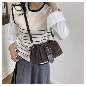 Detail of dark brown suede baguette bag with large vintage buckle on shoulder strap