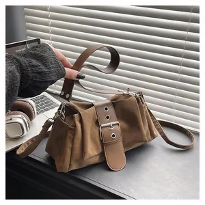 Close-up of brown suede baguette bag with pleated side and metallic buckle strap detail