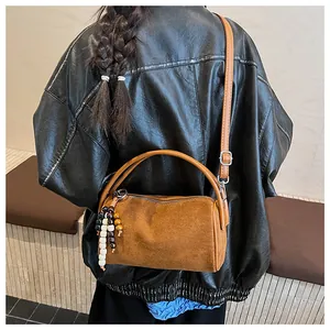 Detail of vintage brown suede cylinder bag with stylish wooden bead pendant and strap