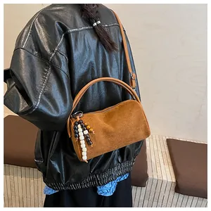 Detail view of vintage brown matte cylinder bag with decorative beads and crossbody strap